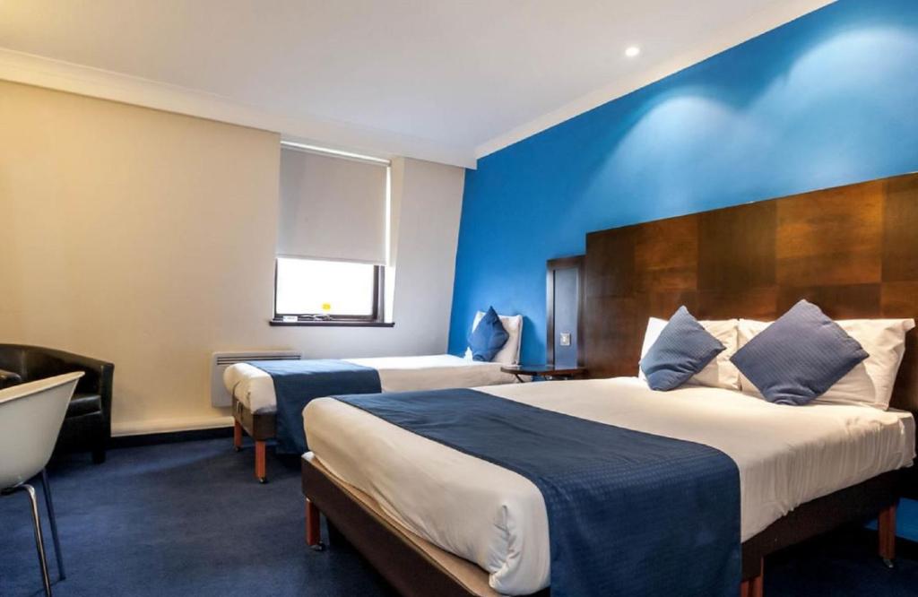 爱丁堡大不列颠爱丁堡酒店的酒店客房设有两张床和蓝色的墙壁。