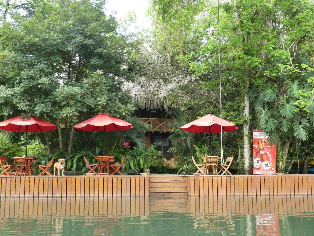 里约杜尔塞Hotel Kangaroo y Restaurante的一间设有桌子和遮阳伞的餐厅,毗邻一片水域