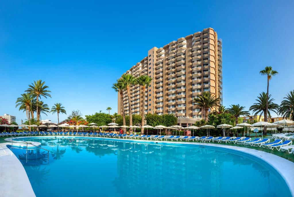 洛斯克里斯蒂亚诺斯索尔阿罗纳特内里费酒店的一座带遮阳伞的大型游泳池和一座大型建筑