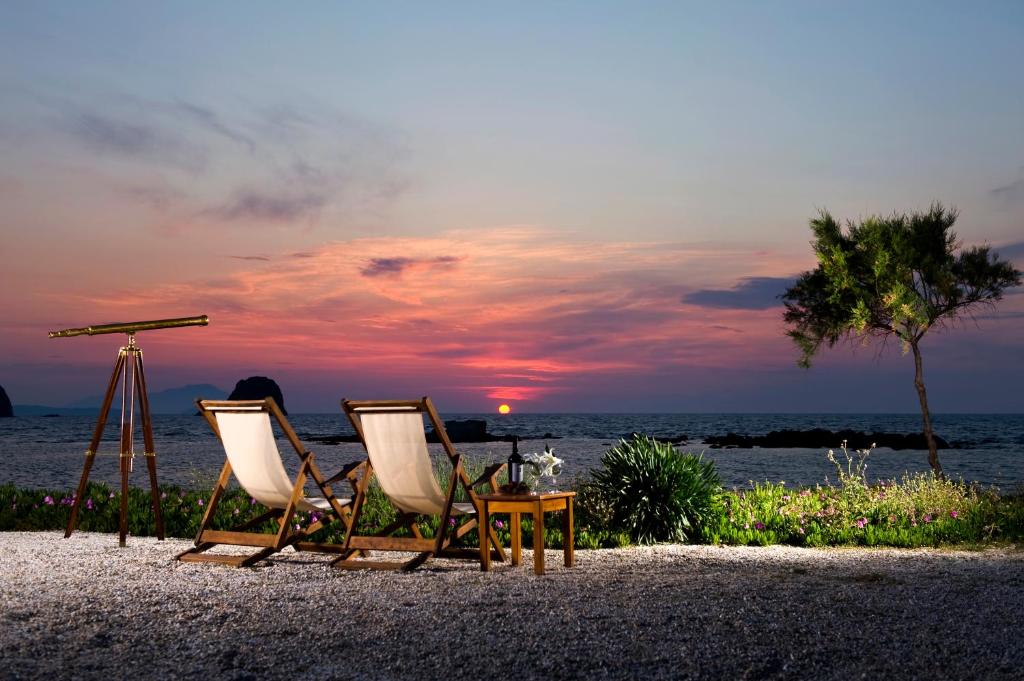 阿波罗尼亚Nefeli Sunset Studios的日落时分海滩上的两把椅子和一张桌子