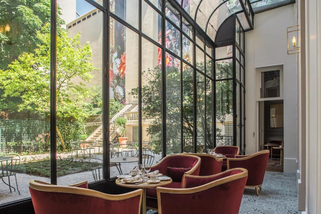 巴黎阿尔弗莱德索米尔酒店的餐厅设有桌椅和大窗户。