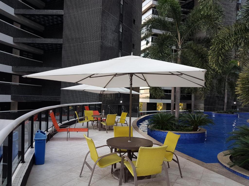 福塔莱萨Landscape Beira mar的桌椅、遮阳伞和游泳池