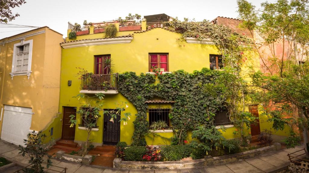 利马Casa Nuestra Peru的黄色房子的一侧有植物