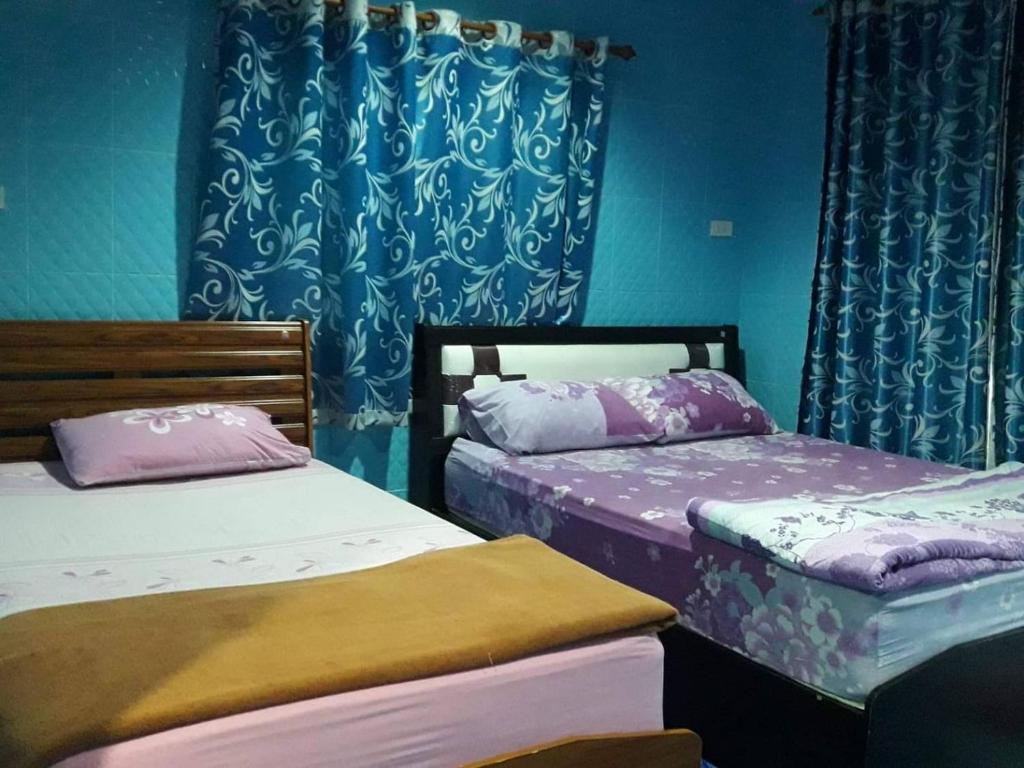 亚兰Muean Fhan Resort Aranyaprathet的配有两张床铺的蓝色墙壁和窗帘