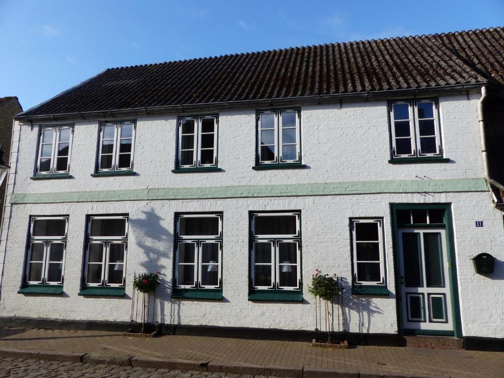 腓特烈Alter Krämerladen von 1732的白色的房子,设有黑窗和绿色百叶窗