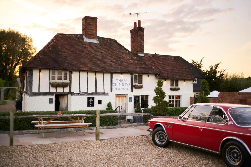 BiddendenThe Three Chimneys Country Pub的停在大楼前的红色汽车