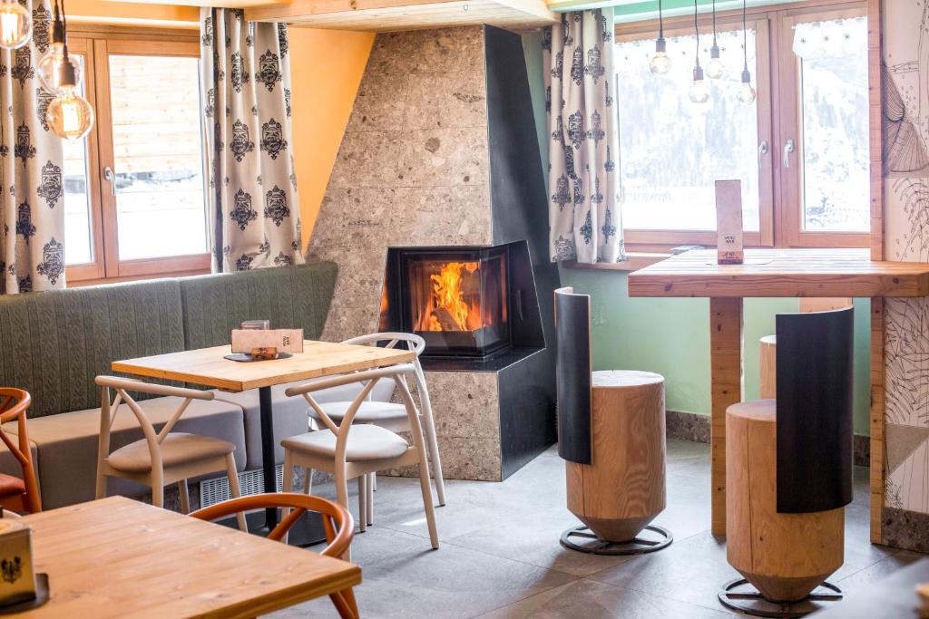 莫尔韦诺Rifugio La Montanara的餐厅设有壁炉,配有桌椅