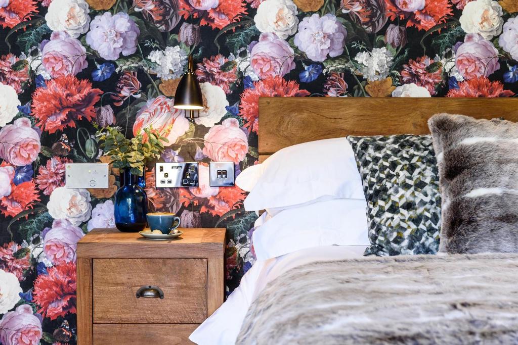 MauldenThe George Inn的一间卧室配有花卉壁纸、一张床和一个床头柜