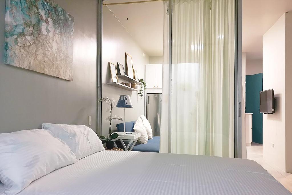 麦克坦GM Rentals SafeStay Apartment at Mactan Airport的卧室配有白色的床和滑动玻璃门
