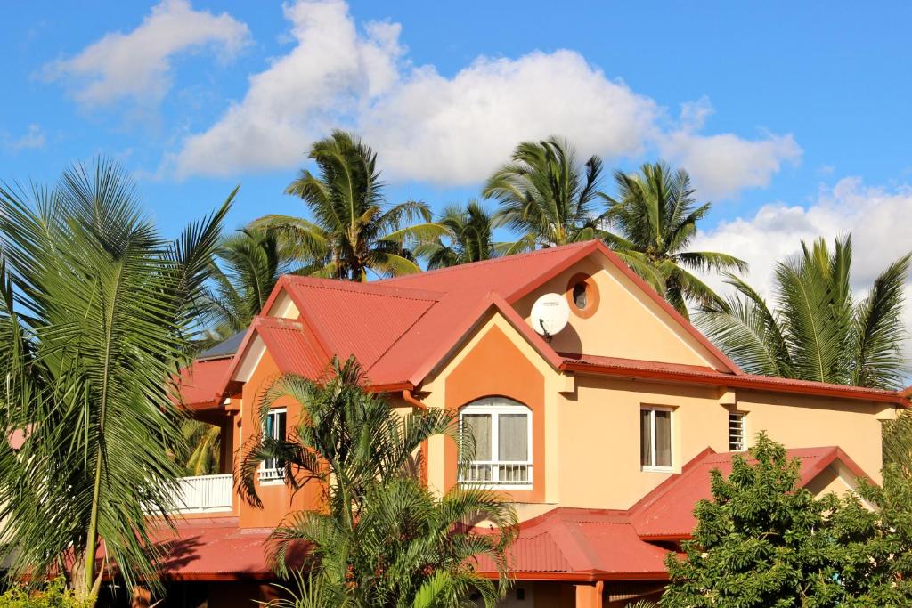圣路易斯La Kaz à l'Étang - Votre Location de Vacances à l'Île de La Réunion的一座红色屋顶和棕榈树的房子