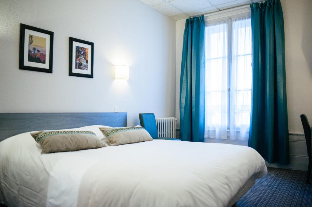 勒阿弗尔Hôtel Carmin的一间卧室配有白色的床、蓝色窗帘和窗户