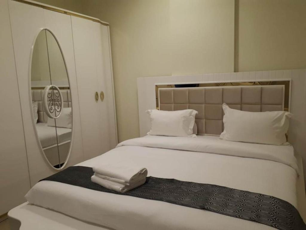 阿吉曼Reef Hotel Aparts (Tabasum Group)的卧室配有一张带镜子的白色大床