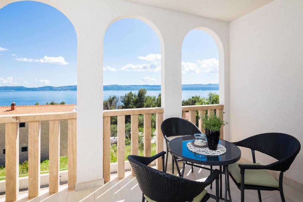 马鲁希奇Appartments Villa Daria的阳台配有桌椅,享有海景。