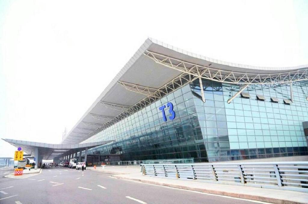 咸阳西安咸阳国际机场一米阳光酒店的一座大型玻璃建筑,前面设有停车场