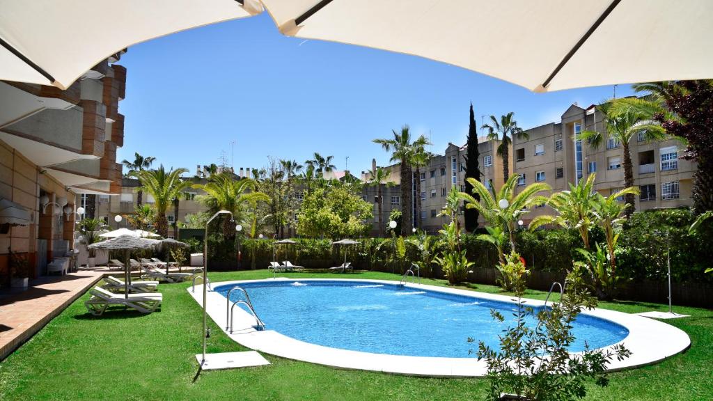 两姐妹Hotel TRH La Motilla的庭院中间的游泳池,配有遮阳伞