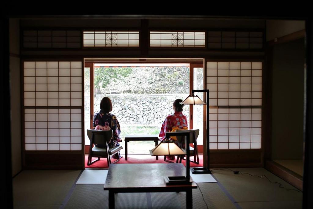 镜野OkutsuHotSpa IkedayaKajikaen的坐在椅子上,看着窗外的两名妇女
