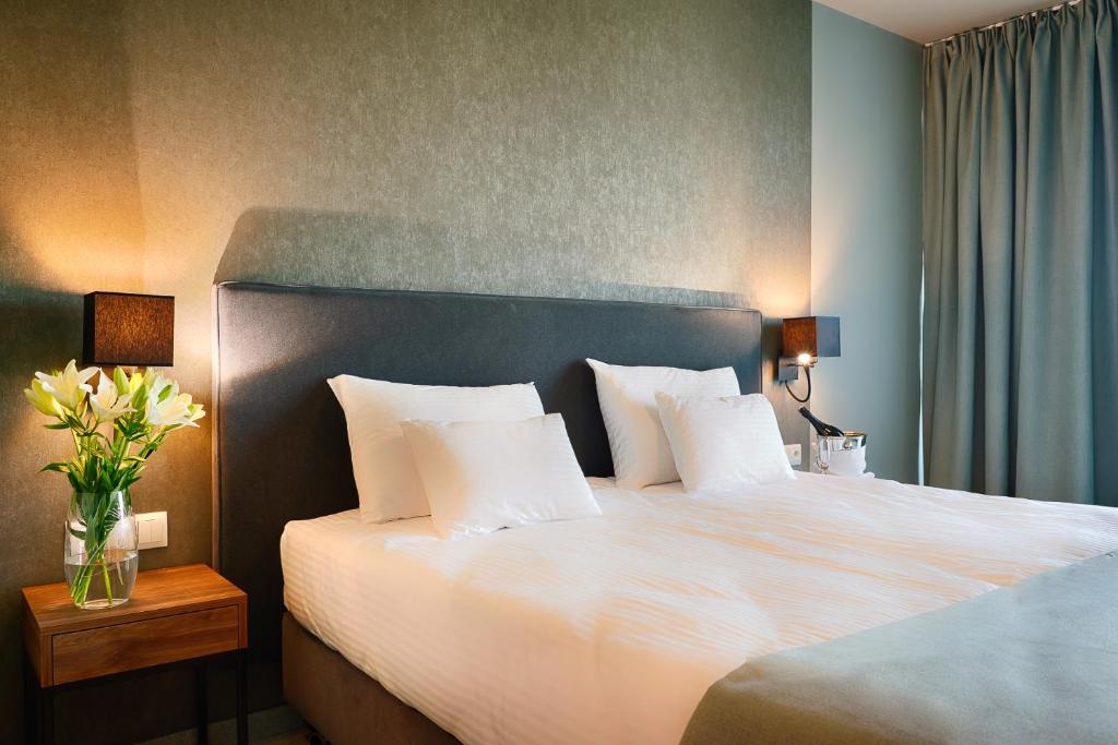 波兹南Focus Hotel Poznań的卧室配有一张带白色床单和枕头的大床。