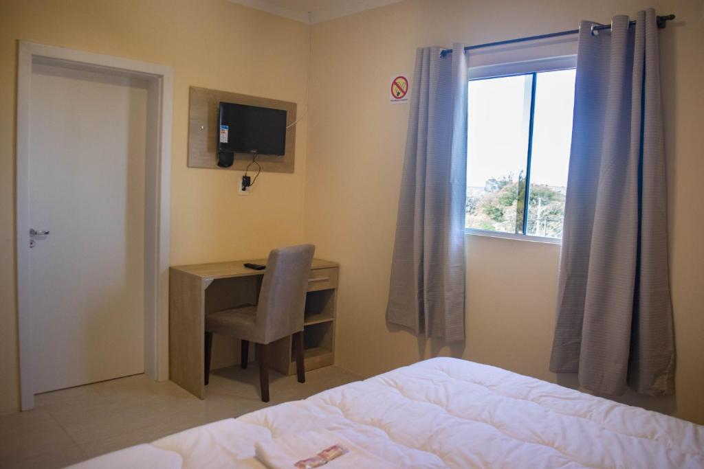 佩洛塔斯Hotel Marrocos的一间卧室配有书桌、床和窗户。