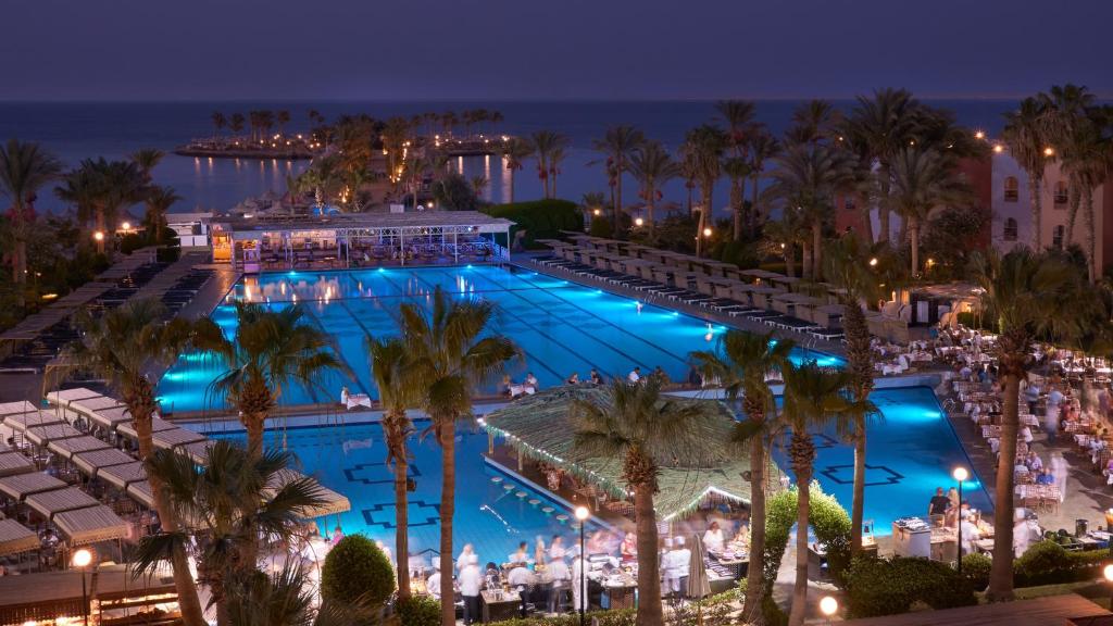 赫尔格达阿拉伯海岸度假酒店的棕榈树泳池和海洋之夜