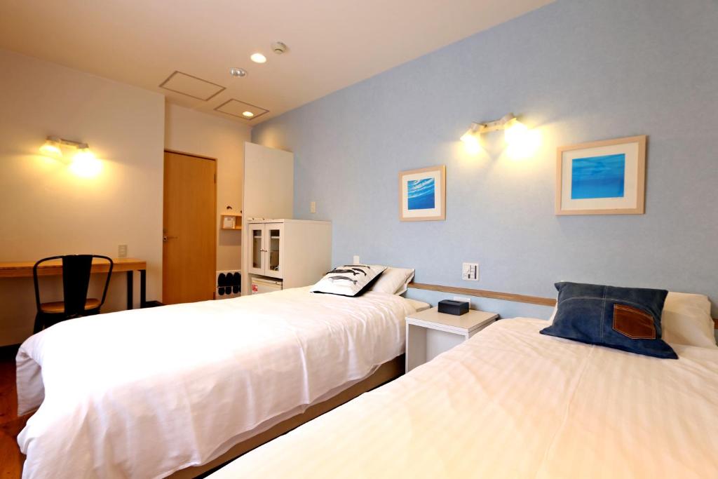 大阪Hotel 3 O'Clock Tennoji的一间卧室配有两张床和一张桌子及椅子