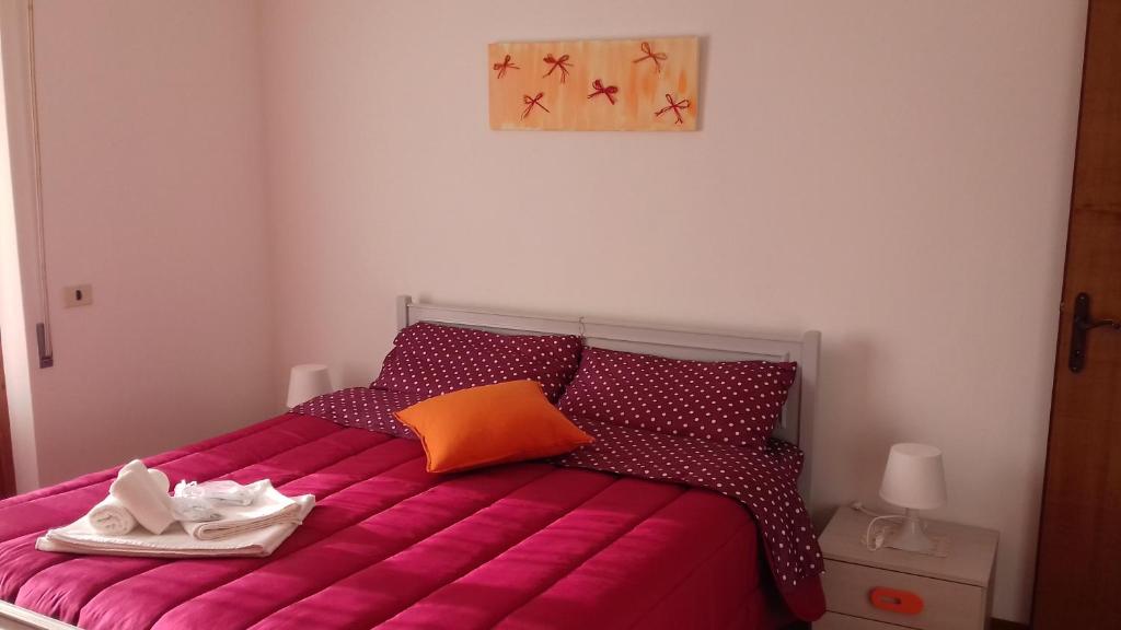 托里塔迪谢纳Casa Cavone的一间卧室配有带粉色床单和橙色枕头的床