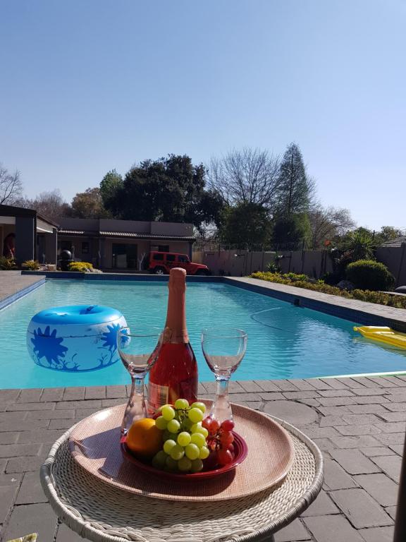 约翰内斯堡Rekky Signature Guesthouse的游泳池旁的水果和酒杯托盘