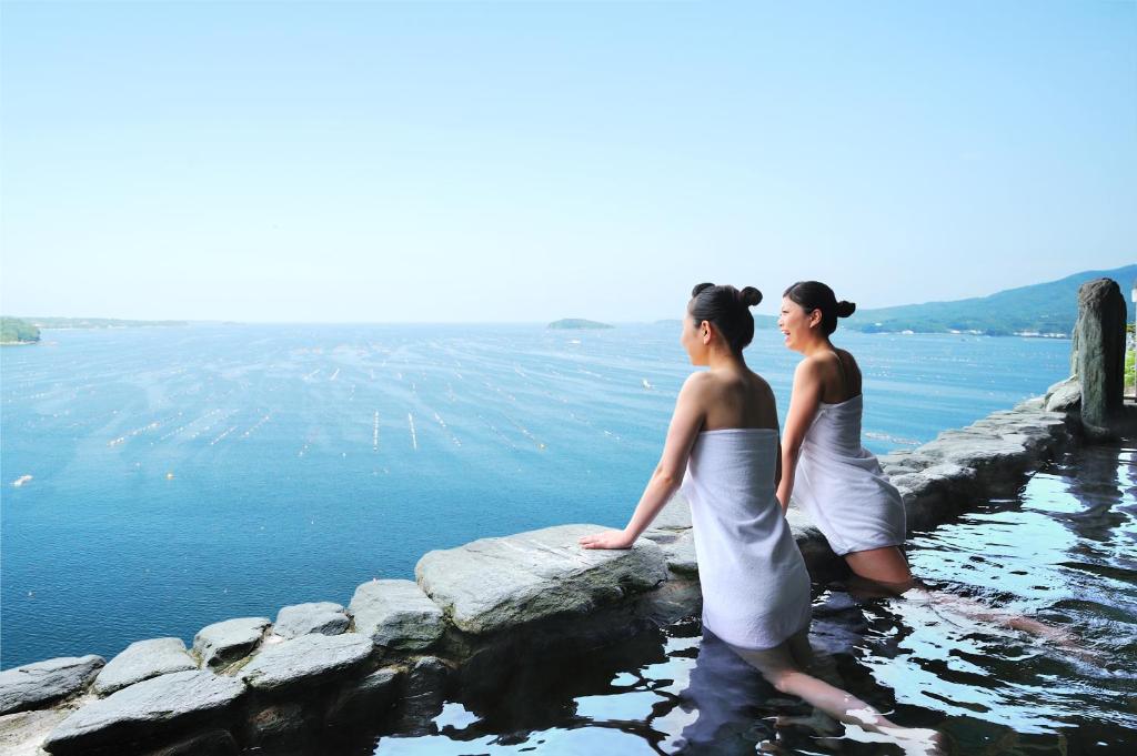 ShizukawaMinami Sanriku Hotel kanyo的两个女人站在水中的岩石上