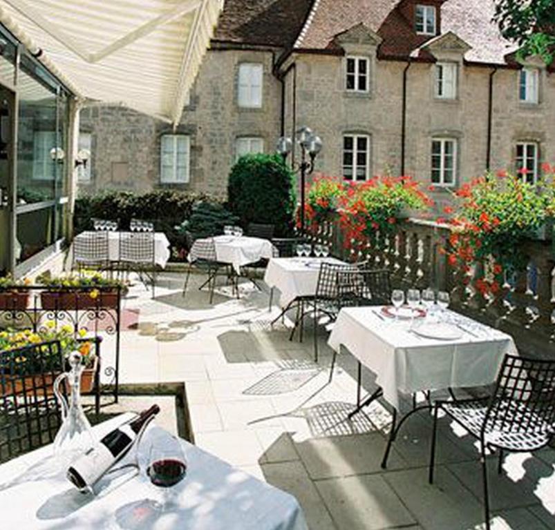 朗格勒Logis Hôtel Le Cheval Blanc的一座配有白色桌椅的庭院和一座建筑