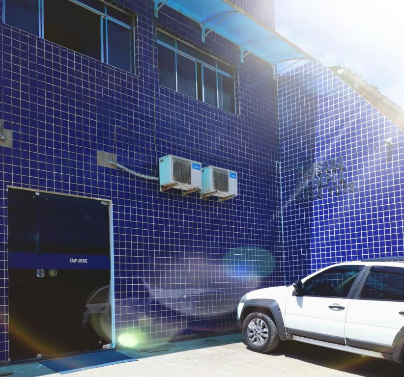 马塞约POUSADA OLÍMPIA的停在蓝色瓷砖建筑前的白色汽车