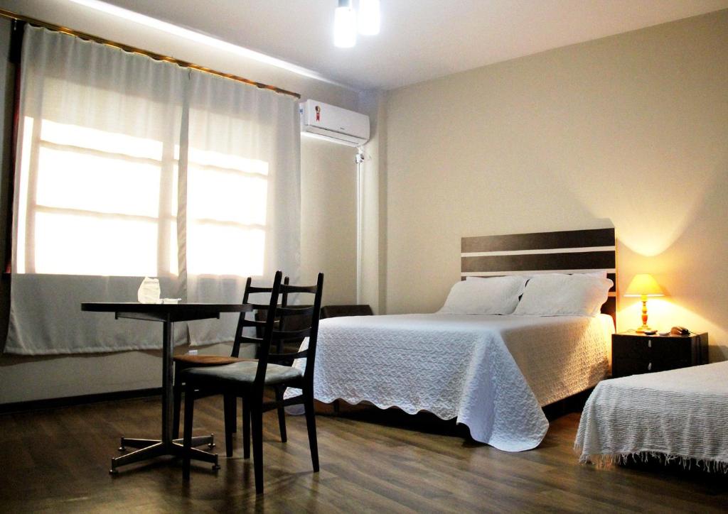 Pôrto UniãoOpera Hotel的一间卧室配有一张床、一张桌子和一个窗户。