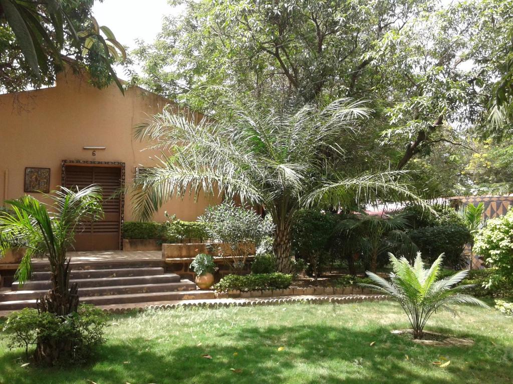 瓦加杜古Hôtel Les Palmiers的一座棕榈树花园,房子前面设有楼梯
