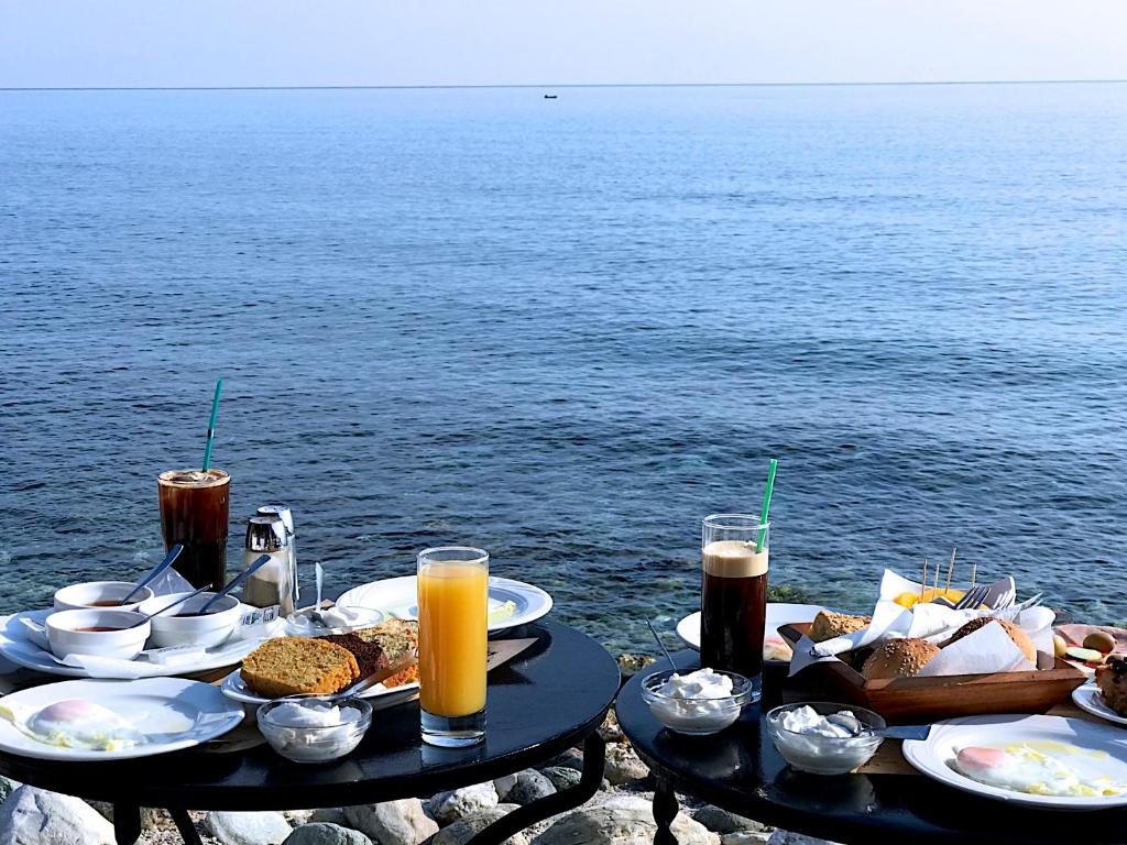 阿吉奥斯伊欧尼斯玛莎酒店的水边的餐桌,有食物和饮料