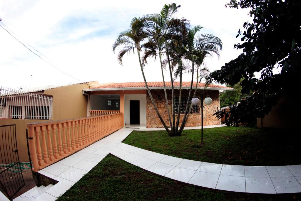 伊瓜苏Casa com varanda próximo da Natureza的院子内有围栏和棕榈树的房子