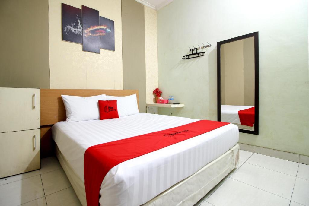 日惹阿迪素拓机场附近3号红门酒店的一间卧室配有一张大床和镜子