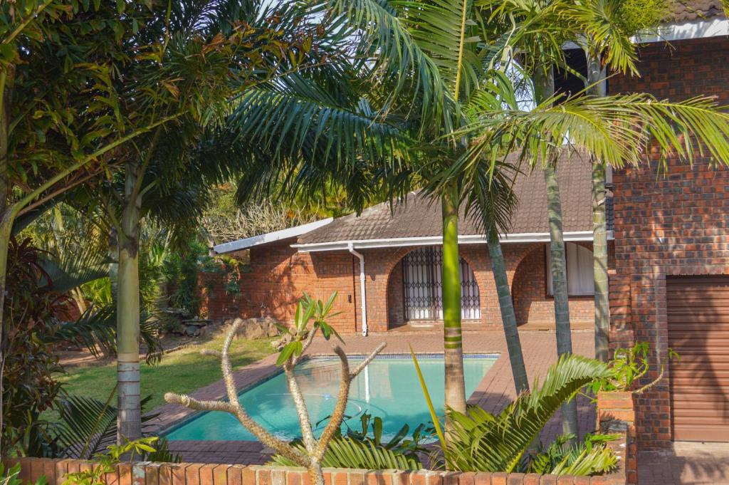 理查兹湾Emangunini Guest house的两棵棕榈树之间的房子,设有游泳池