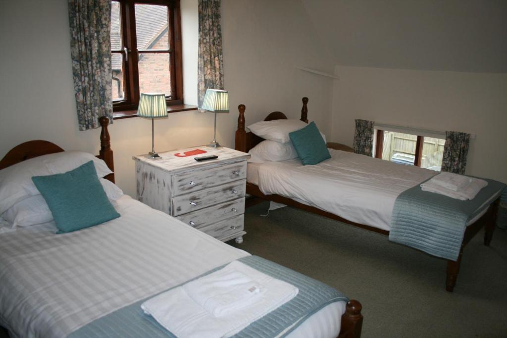 马奇温洛克The Talbot Inn的一间卧室配有两张床和一个带两盏灯的梳妆台。