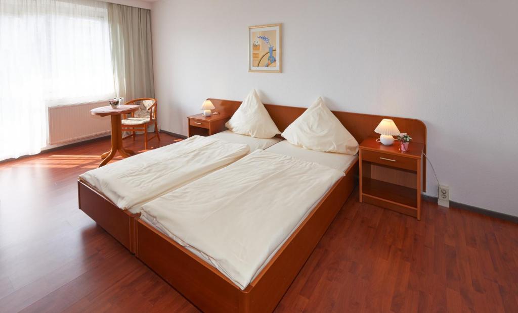 Rötha莱比锡 - 勒塔阿尔法公寓酒店的卧室配有一张带白色床单和木地板的大床。