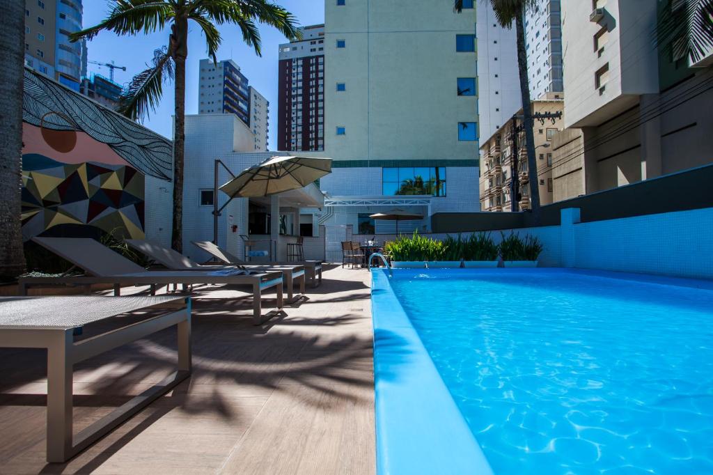 巴拉奈里奥-坎布里乌Santa Inn Hotel的一个带躺椅和遮阳伞的游泳池