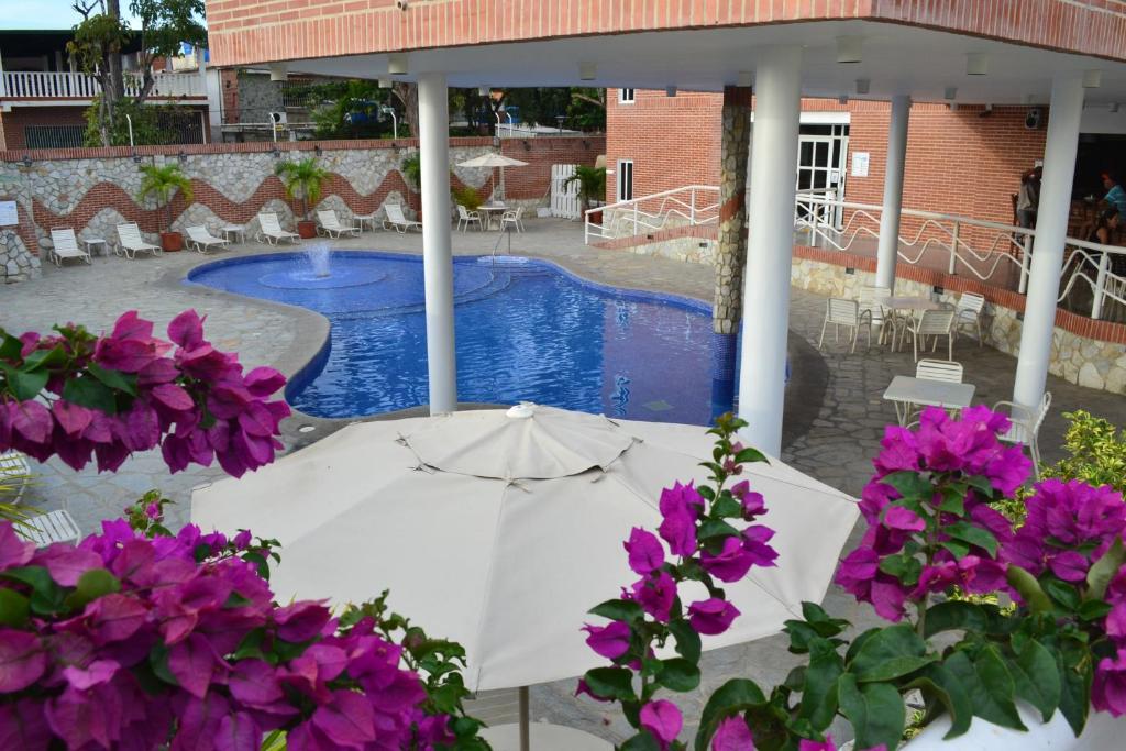 帕拉亚格兰德Hotel Villa Playa Grande的游泳池旁的白色遮阳伞和紫色鲜花