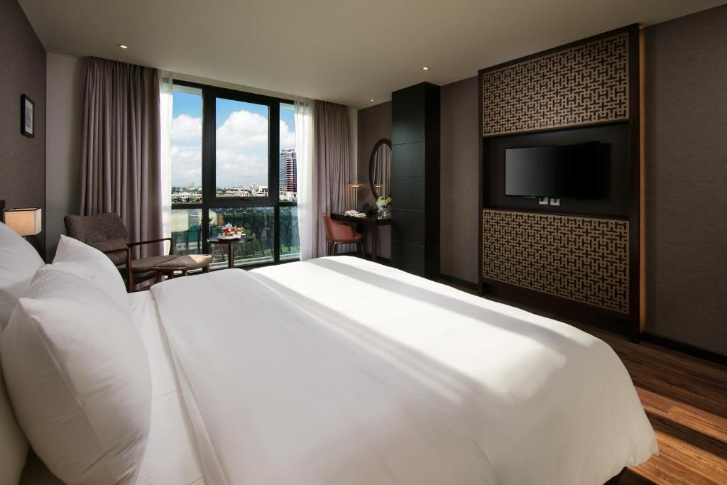 河内壮观Spa酒店的一张大白色床,位于酒店客房,配有平面电视