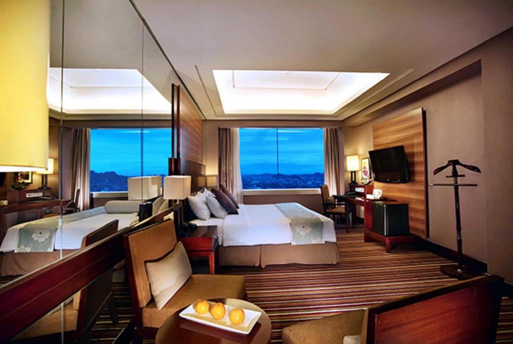 沙马林达ASTON Samarinda Hotel and Convention Center的酒店客房设有两张床和大窗户。
