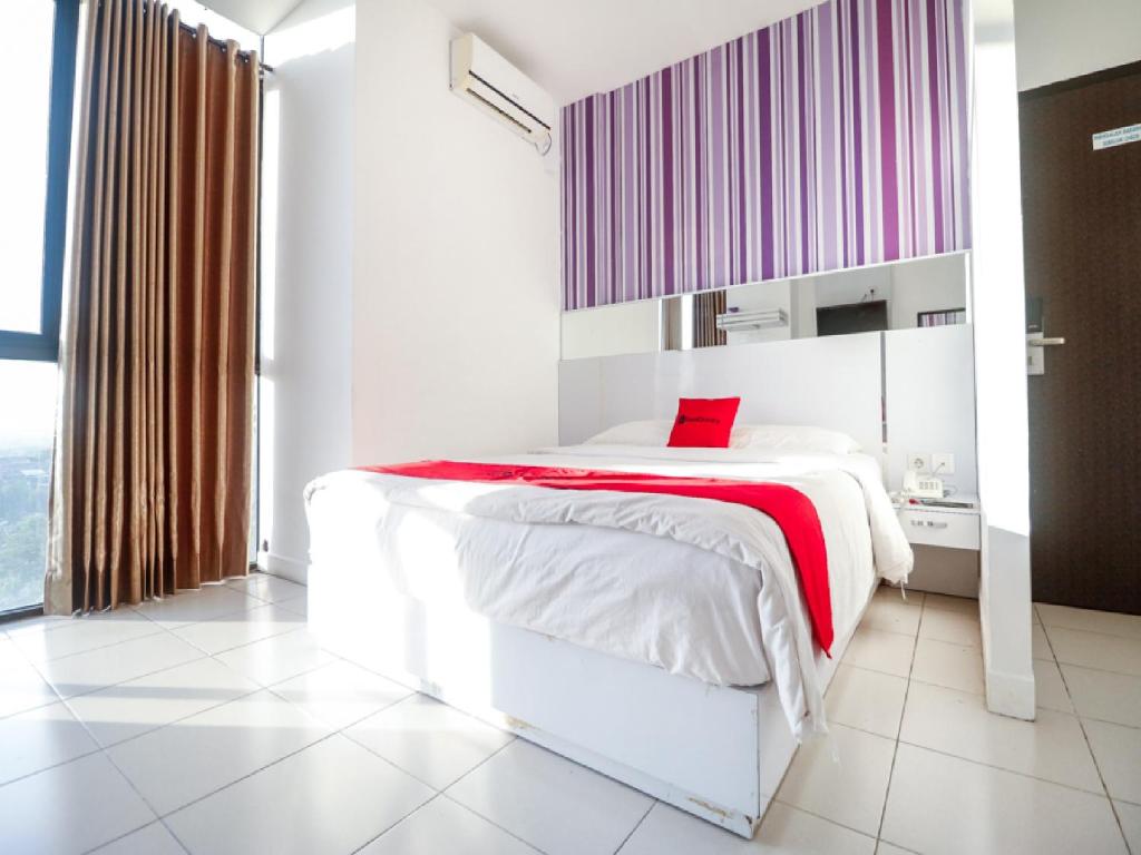巴厘巴板RedDoorz near Terminal Batu Ampar的卧室配有一张带红色毯子的白色床