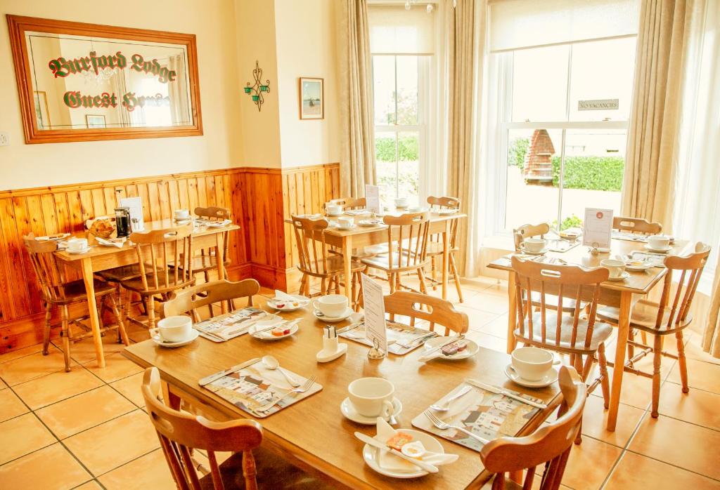 ArdglassBurford Lodge Guest House的一间带桌椅的用餐室和大窗户