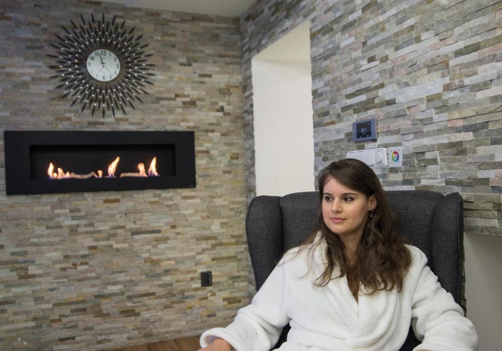 捷克捷欣Wellness Apartmán Relax的坐在壁炉前椅子上的女人