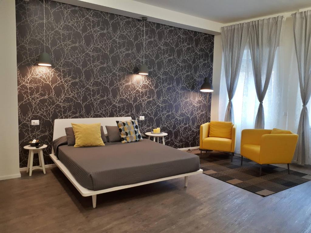 米兰马尔科纳24公寓式酒店的一间卧室配有一张床和两张黄色椅子