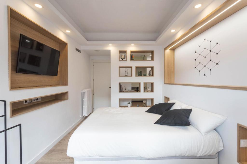 蓬费拉达Bierzo Habita Apartments的卧室配有白色的床和平面电视。