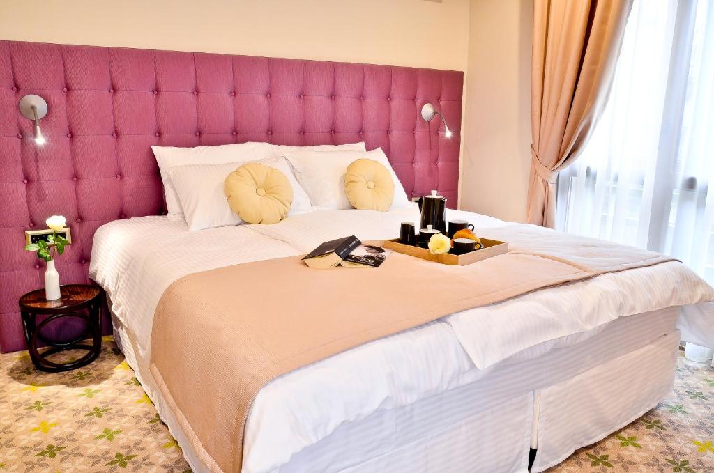 克卢日-纳波卡卡皮托利纳城市时尚酒店的一间卧室配有一张带粉红色床头板的大床