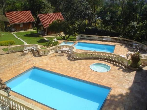 皮拉卡亚Pousada Casa Amarela的砖砌庭院设有两个大型蓝色游泳池