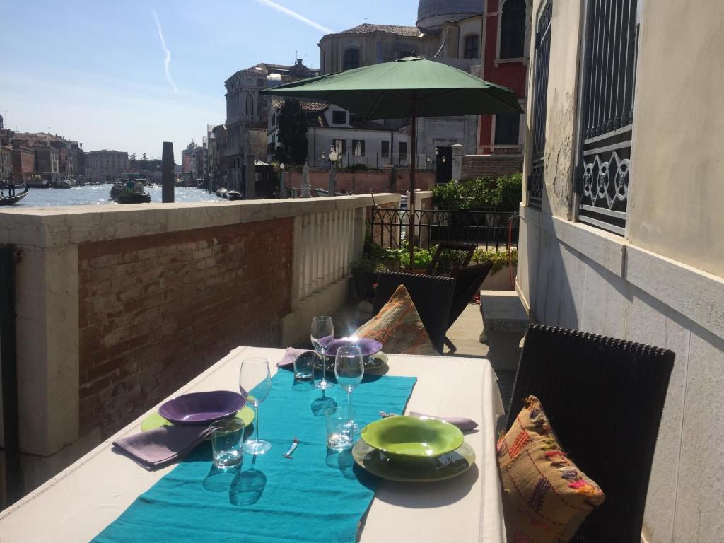 威尼斯Terrazza Momon的阳台上的桌子上摆放着盘子和玻璃杯