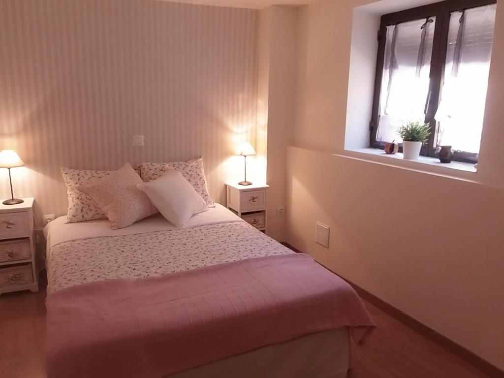 巴尔韦尔德德洛萨罗约斯Casa Rural Los Robles的一间卧室配有带2个床头柜和2个窗户的床